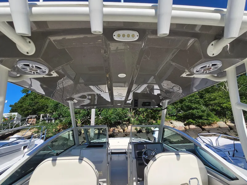 Slide: The Image of 2020 Stingray 269 DC boat interior with speakers and canopy, docked near lush greenery. - 10