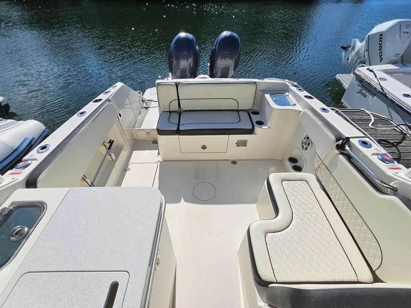Slide: The Image of 2020 Stingray 269 DC boat interior with seating and storage, docked on calm water. - 14