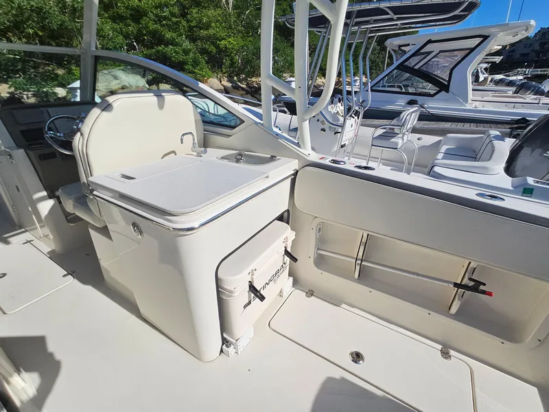Slide: The Image of 2020 Stingray 269 DC boat interior with seating and storage, docked near other boats. - 15