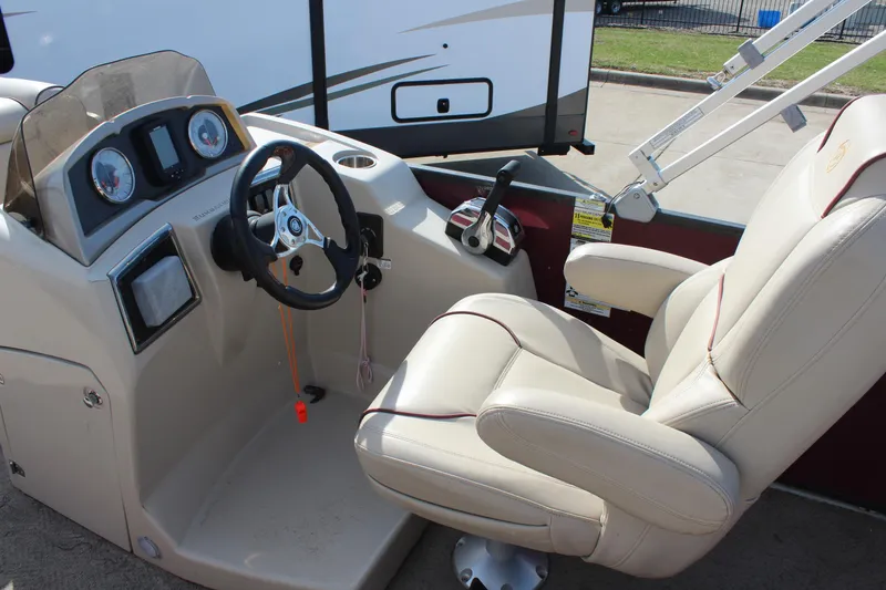 Slide: The Image of 2015 Premier 220 SunSation boat cockpit with steering wheel and beige captain's chair. - 10