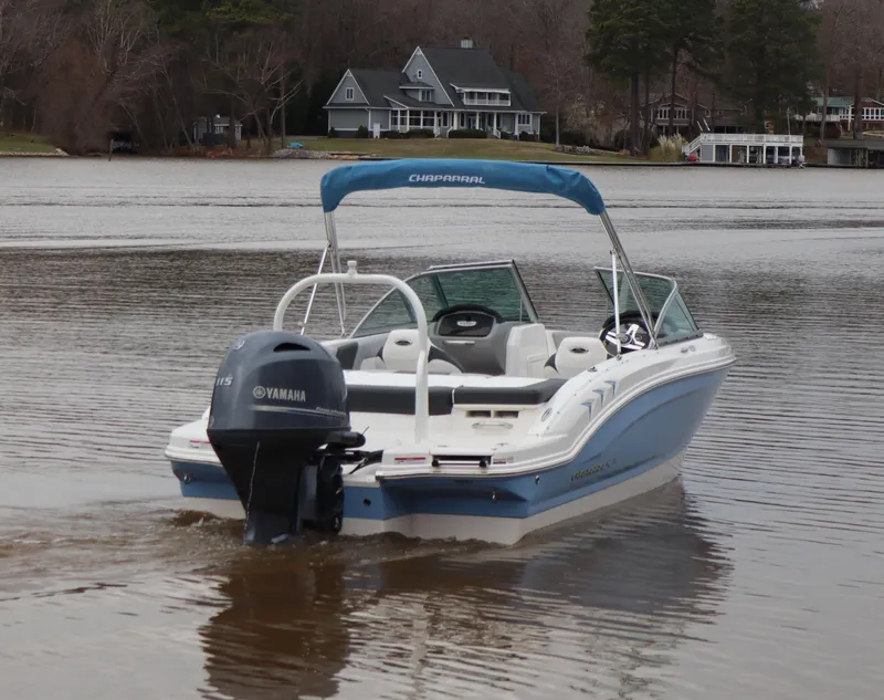 Slide: The Image of 2024 Chaparral 19 SSi OB boat on a calm lake with houses in the background. - 3