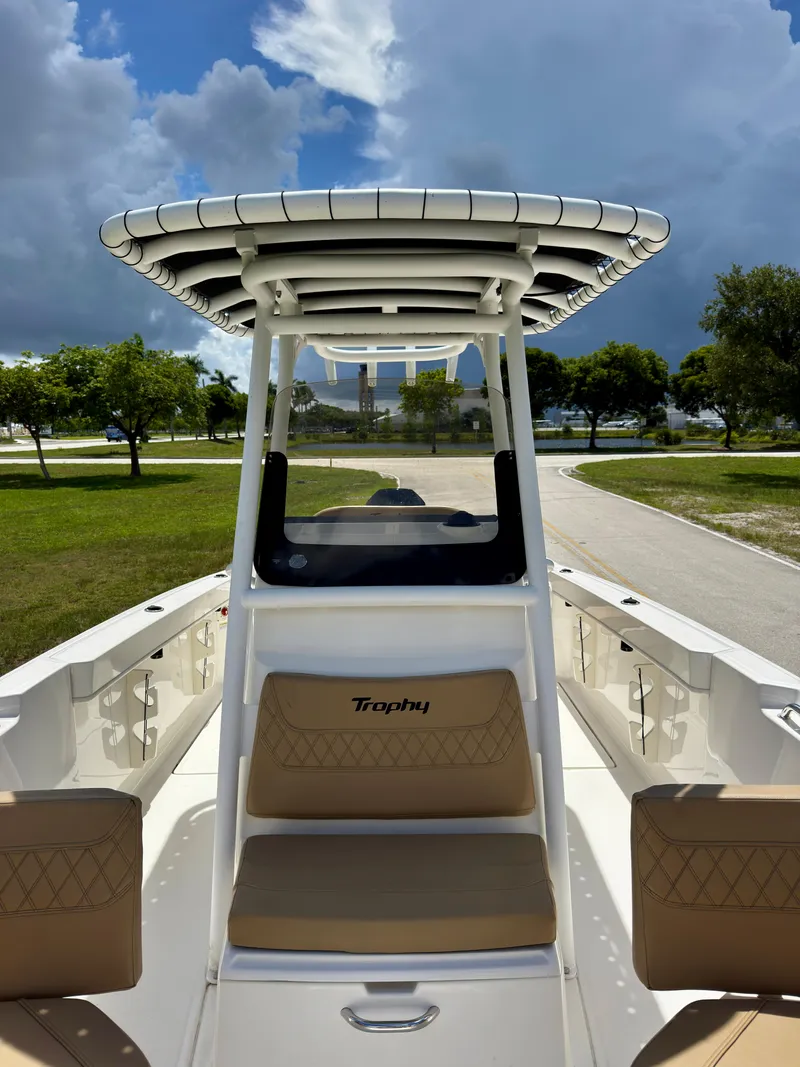 Slide: The Image of 2023 Bayliner Trophy T24CC boat with seating, under a cloudy sky, parked on a road. - 11