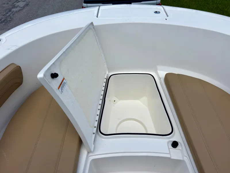 Slide: The Image of 2023 Bayliner Trophy T24CC boat storage compartment with open lid and cushioned seating. - 29