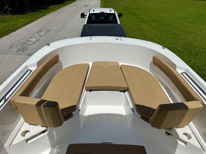 Slide: The Image of 2023 Bayliner Trophy T24CC boat interior with tan seating, parked on a road. - 7