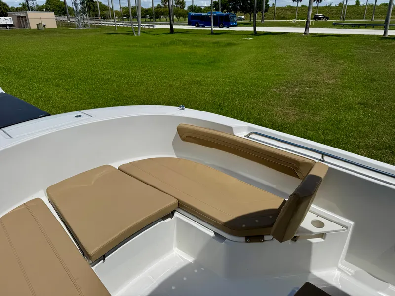 Slide: The Image of 2023 Bayliner Trophy T24CC boat interior with tan seating and green grass background. - 8