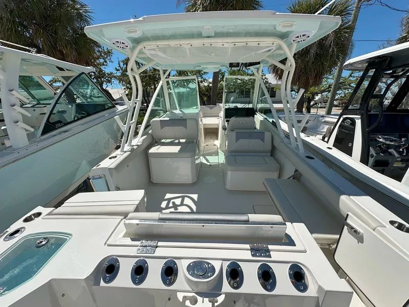 Slide: The Image of 2025 Sailfish 276 DC boat interior with seating, rod holders, and canopy under a clear blue sky. - 11