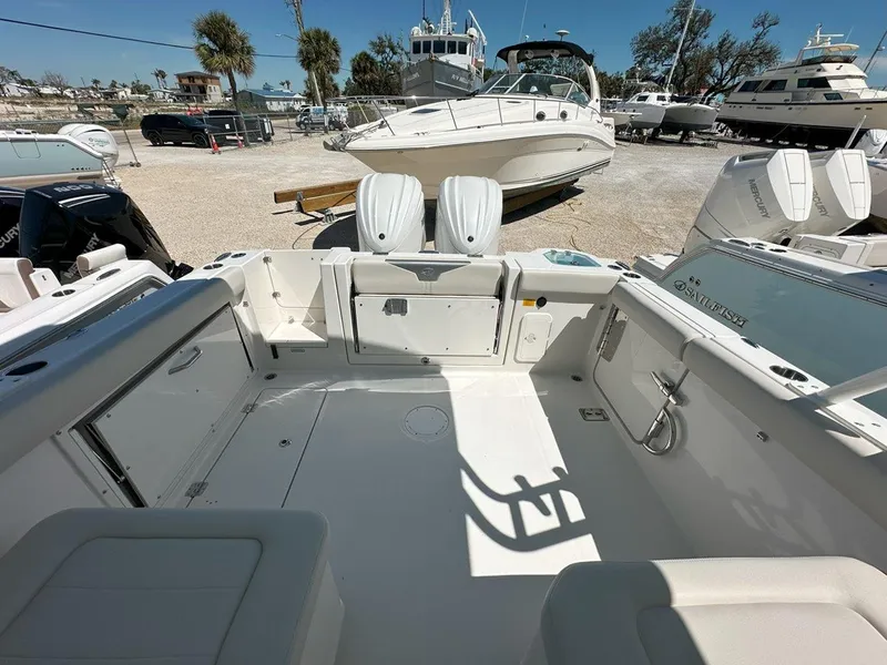 Slide: The Image of 2025 Sailfish 276 DC boat interior with dual outboard motors in a marina setting. - 37