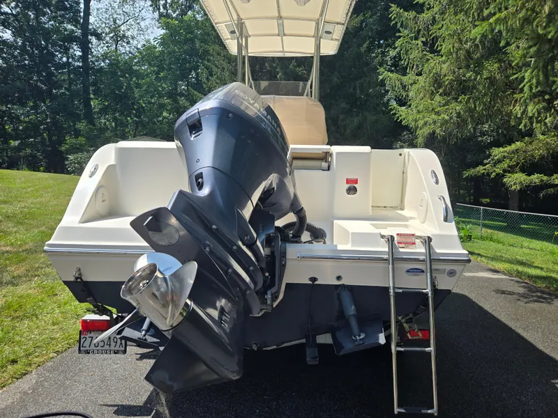 Slide: The Image of 2015 Cobia 201 Center Console boat with outboard motor and ladder, parked outdoors. - 3