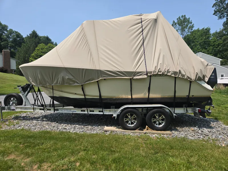 Slide: The Image of 2015 Cobia 201 Center Console boat covered on trailer, parked on grass. - 5