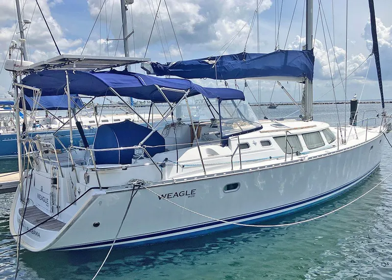 The Image of 2002 Jeanneau 43DS sailboat docked, featuring blue canopy and sleek white hull. - 0