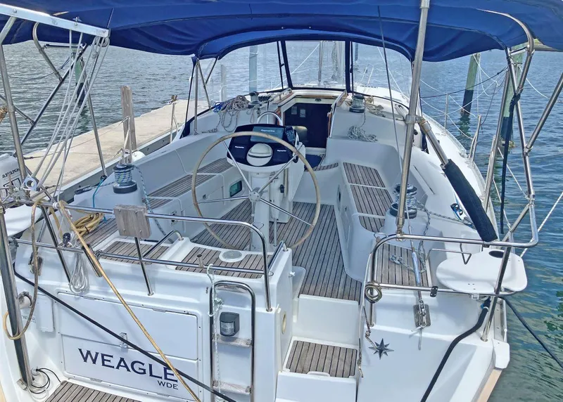 Slide: The Image of 2002 Jeanneau 43DS sailboat with blue canopy docked at marina. - 2