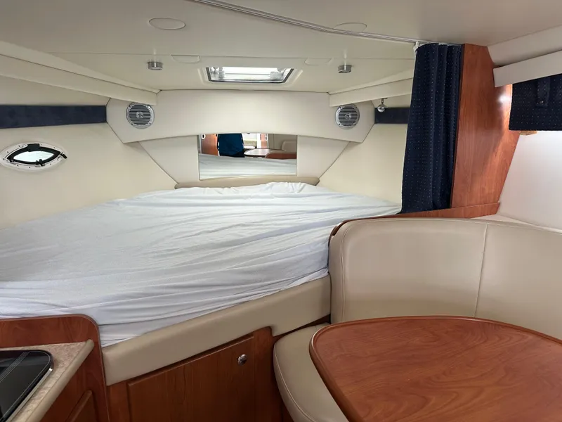 Slide: The Image of 2008 Bayliner 300SB cabin interior with bed, seating, and wood accents. - 14