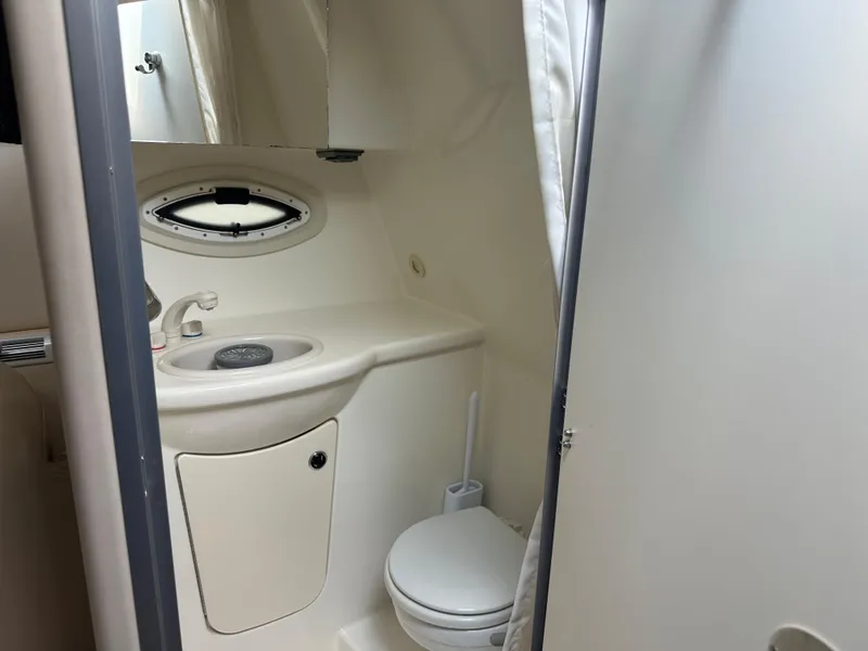 Slide: The Image of 2008 Bayliner 300SB boat bathroom with sink, toilet, and porthole window. - 19