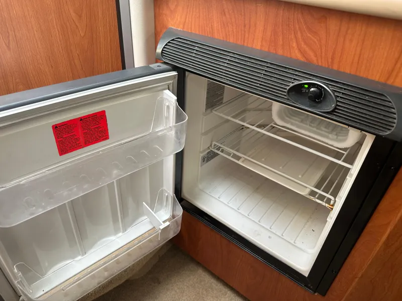 Slide: The Image of Open refrigerator inside a 2008 Bayliner 300SB boat, showing empty shelves and door compartments. - 24