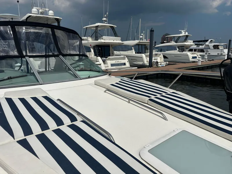 Slide: The Image of 2008 Bayliner 300SB yacht with striped sunbeds docked at marina under cloudy sky. - 27