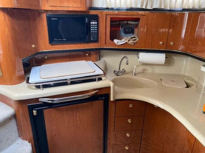 Slide: The Image of 1998 Sea Ray Sundancer 370 yacht kitchen with microwave, sink, and wooden cabinetry. - 14