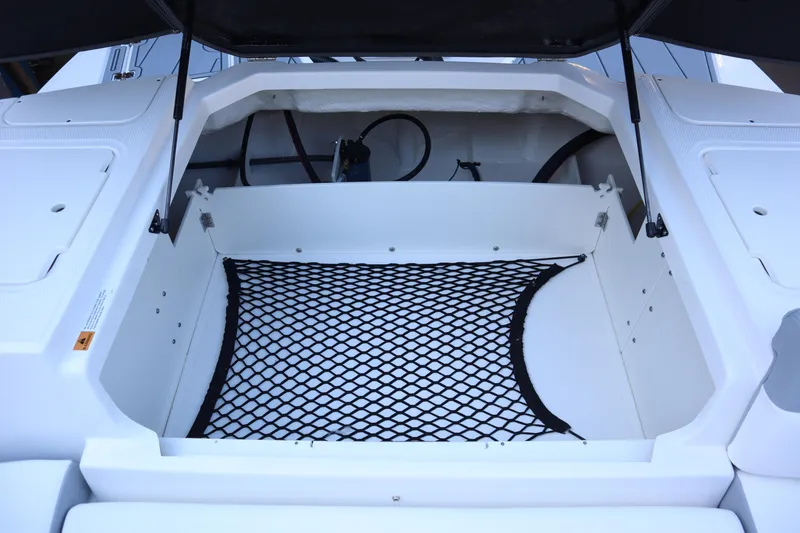 Slide: The Image of 2024 Chaparral 23 SSi OB boat storage compartment with netting and hydraulic supports. - 17