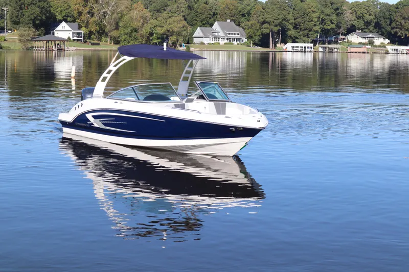 Slide: The Image of 2024 Chaparral 23 SSi OB boat on a serene lake with houses in the background. - 4