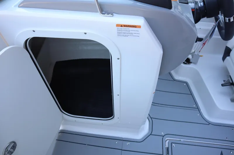 Slide: The Image of 2024 Chaparral 23 SSi OB boat interior storage compartment with open door. - 7