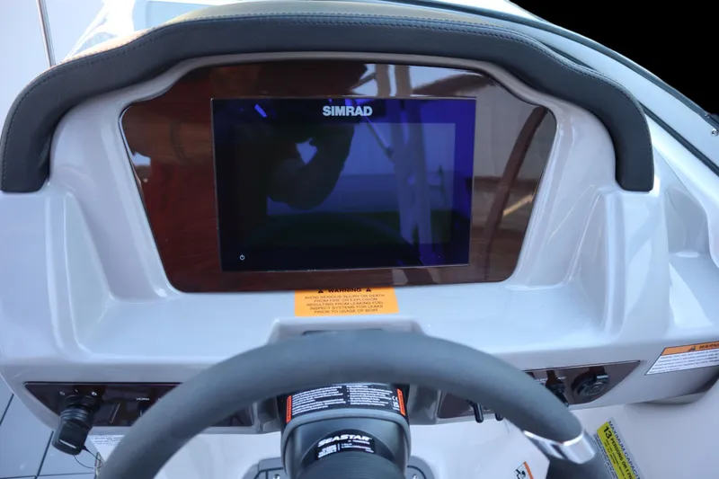 Slide: The Image of 2024 Chaparral 23 SSi OB dashboard with Simrad display and steering wheel. - 9