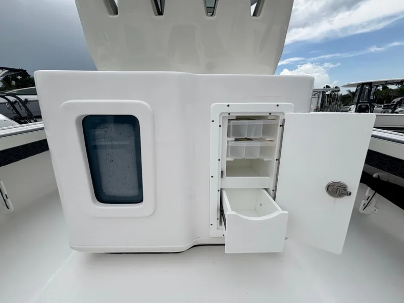 Slide: The Image of 2026 Tidewater 2700 Carolina Bay boat storage compartment with open door and drawers. - 10
