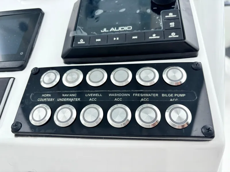Slide: The Image of Control panel of 2026 Tidewater 2700 Carolina Bay boat with labeled buttons and JL Audio system. - 16