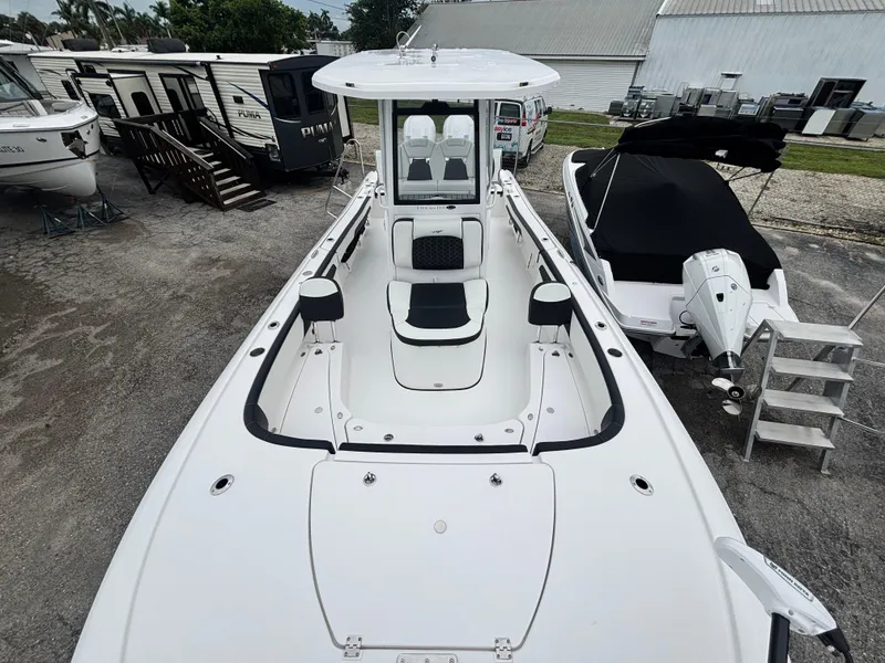 Slide: The Image of 2026 Tidewater 2700 Carolina Bay boat, white exterior, parked near RVs and other boats. - 21