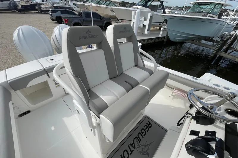 Slide: The Image of 2026 Regulator 25 boat interior with dual seats and steering wheel at marina. - 18