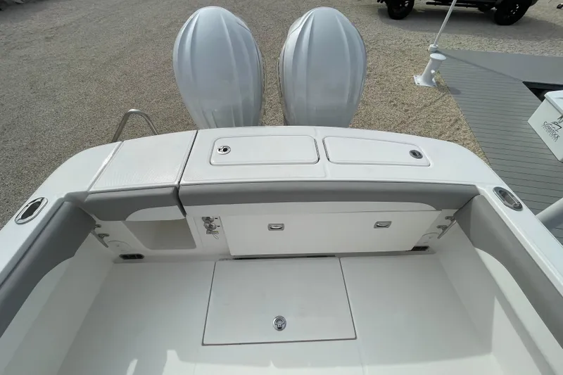 Slide: The Image of 2026 Regulator 25 boat deck with dual outboard motors, featuring storage compartments. - 24