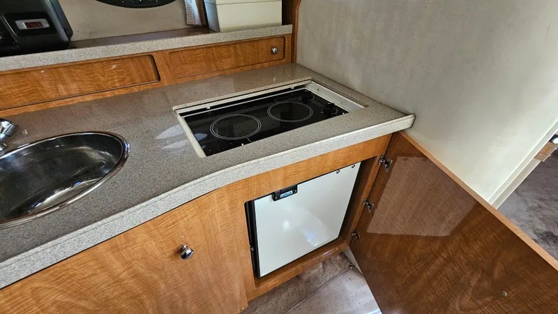 Slide: The Image of 2003 Regal Commodore 3260 yacht kitchen with stove, sink, and wooden cabinetry. - 28