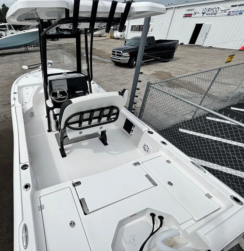 Slide: The Image of 2026 Tidewater 2210 Carolina Bay boat with center console and seating, parked near a fence. - 9
