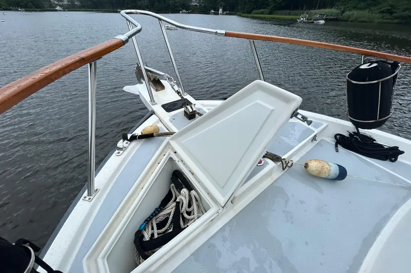 Slide: The Image of Bow of a 1998 Monk 36 boat with open hatch and ropes on a calm river. - 11