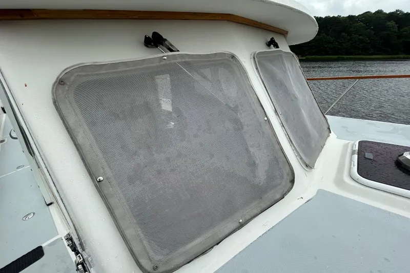 Slide: The Image of 1998 Monk 36 boat windows with protective covers, docked by a river. - 15