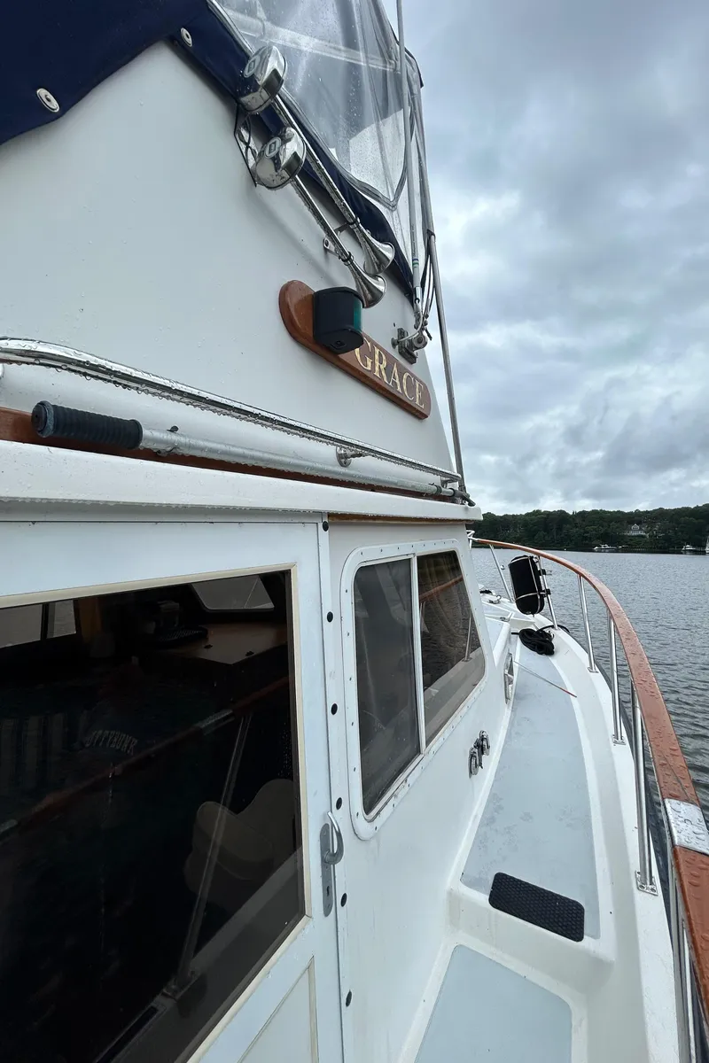 Slide: The Image of 1998 Monk 36 boat on water, cloudy sky, wooden deck, and cabin windows. - 18