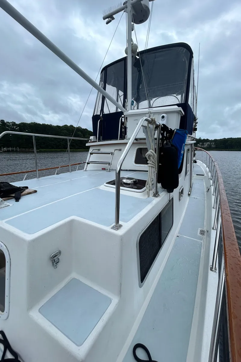 Slide: The Image of 1998 Monk 36 boat on water, featuring a spacious deck and enclosed cockpit. - 21