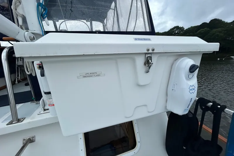 Slide: The Image of White storage compartment on a 1998 Monk 36 boat, labeled for life jackets and emergency flares. - 24