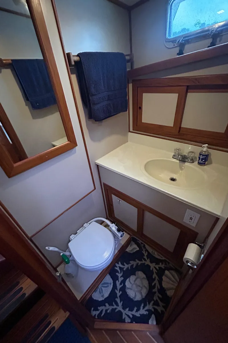 Slide: The Image of Compact bathroom in a 1998 Monk 36 boat, featuring a sink, toilet, and wooden accents. - 7