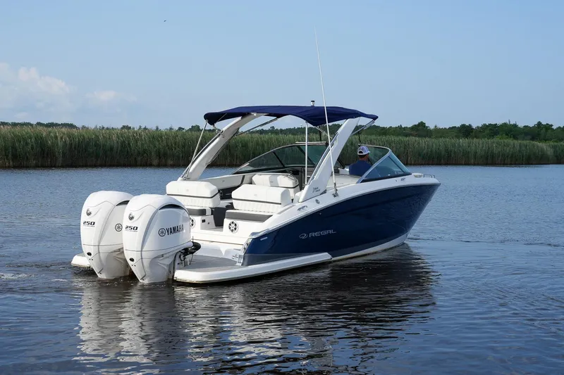 Slide: The Image of 2023 Regal 29 OBX boat with twin Yamaha engines on a calm lake. - 10