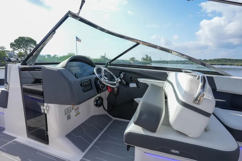 Slide: The Image of 2023 Regal 29 OBX boat interior with modern dashboard and steering, overlooking serene waters. - 18