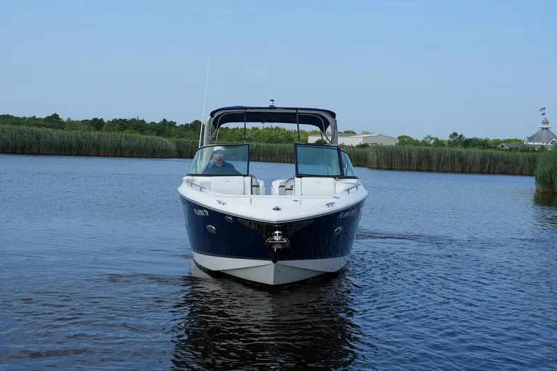 Slide: The Image of 2023 Regal 29 OBX boat cruising on a calm river with lush greenery. - 4