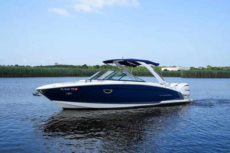 Slide: The Image of 2023 Regal 29 OBX boat cruising on a calm river with lush greenery in the background. - 6