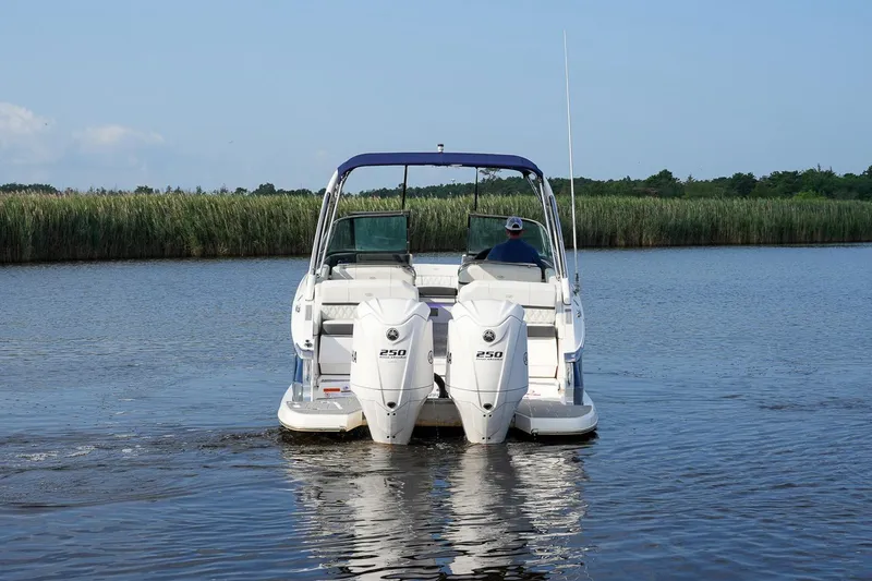 Slide: The Image of 2023 Regal 29 OBX boat cruising on a calm river with lush greenery. - 9