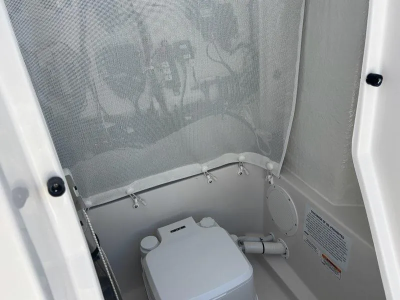 Slide: The Image of 2026 Sailfish 232 CC boat interior with compact marine toilet and privacy curtain. - 18