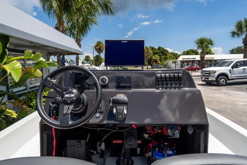 Slide: The Image of 2021 SCB S22 boat dashboard with steering wheel and control panel, surrounded by palm trees. - 10