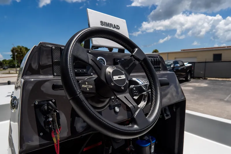 Slide: The Image of 2021 SCB S22 boat dashboard with steering wheel and Simrad display under a blue sky. - 13