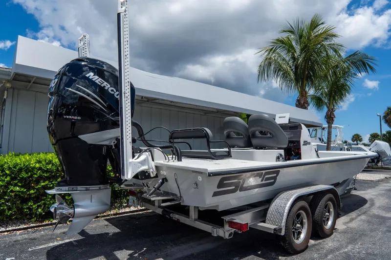 Slide: The Image of 2021 SCB S22 boat with Mercury engine, parked on trailer under palm trees. - 2