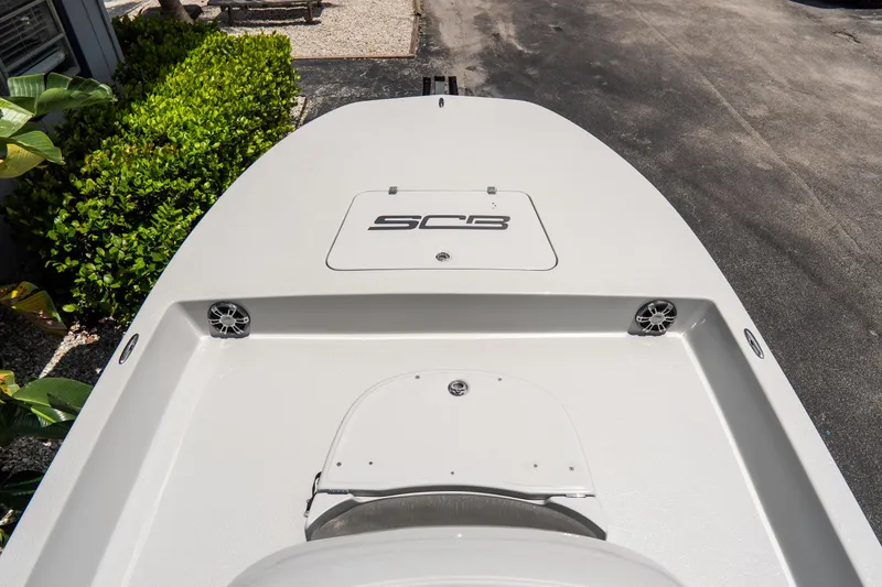 Slide: The Image of 2021 SCB S22 boat deck with storage hatch and speakers, surrounded by greenery. - 6