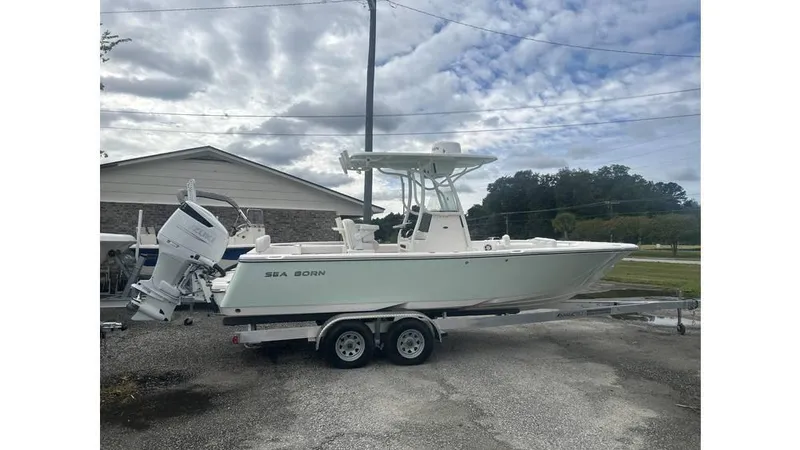 The Image of 2024 Sea Born LX22 Center Console boat on trailer, parked outdoors under cloudy sky. - 0