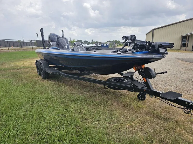 Slide: The Image of 2026 Skeeter ZXE20 boat on trailer, parked on grass near industrial building. - 8
