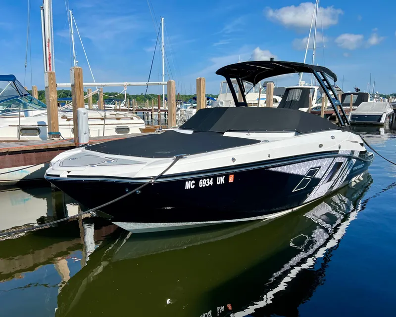 The Image of 2019 Monterey M6 boat docked in marina, reflecting on calm water under blue sky. - 1